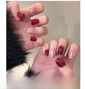 Detail of red press-on nails with 3D bows and rhinestones on black fur background