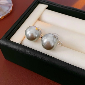 Macro shot of silver-tone clip-on earrings with large iridescent grey pearls in jewelry box