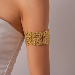 Gros plan sur le bracelet de bras ajouré doré avec motifs floraux et texture rétro