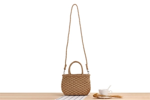 Chic beige straw woven tote bag with handle and shoulder strap on a wooden table