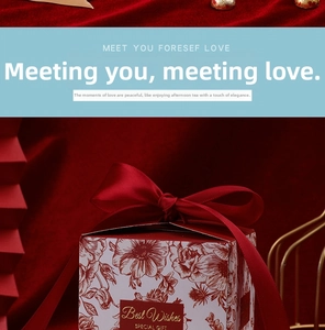 Close-up of elegant wedding favor box with red satin bow and gold foil Best Wishes label