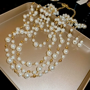 Close-up of multilayer pearl necklace and earrings set on a golden metal tray