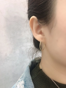 Close-up of a model wearing a minimalist round gold hoop earring with a stylish denim jacket