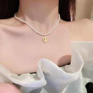 Detail of vintage tulip-inspired green oval gemstone pendant with pearl necklace on neck