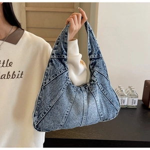 Détail du sac fourre-tout en denim bleu avec surpiqûres décoratives et design en patchwork
