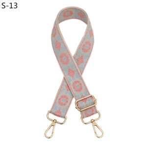 Detail of embroidered ethnic strap with floral patterns and gold metal lobster clasps