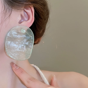 Detail of a light green translucent irregular resin earring with water ripple texture