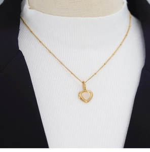 Detailed close-up of a gold heart necklace with natural white mother of pearl inlay