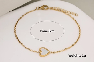 Detail view of a gold heart bracelet with white shell inlay and lobster clasp
