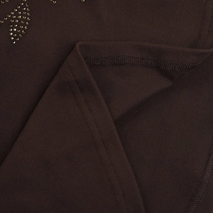 Détail macro du tricot marron foncé avec strass dorés et coutures à aiguilles doubles