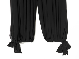 Détail des poignets élastiques avec nœuds décoratifs sur les jambes de la combinaison