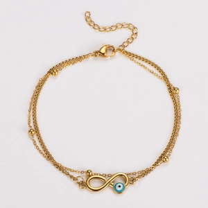 Detail of double-layer gold anklet with blue evil eye and infinity charm on white background