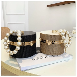 Detail of luxury rhinestone evening bags in black and gold with large pearl handles