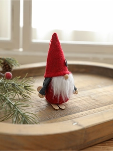 Close-up of handmade Christmas gnome with a red felt hat and wooden skis on a rustic tray