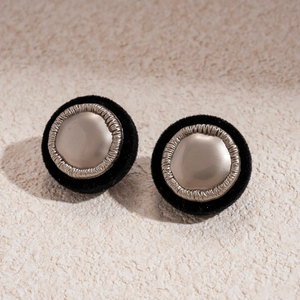 Detailansicht runder Vintage-Ohrstecker in Schwarz mit goldener Metallmitte und Beflockung