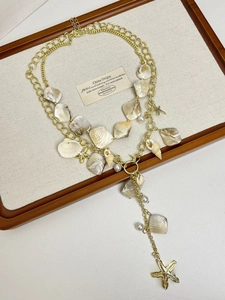 Detail of double-layered gold chain with natural iridescent shells and starfish pendant