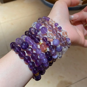 Detailed shot of layered amethyst bead bracelets with gold floral spacers on wrist