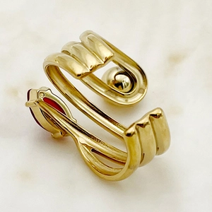 Detailed macro view of a gold-plated multi-layer ring with red gemstone and metal sphere