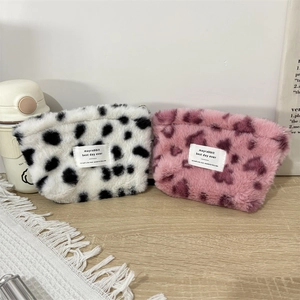 Close-up of plush square pouches in cow and leopard prints with soft fabric textures
