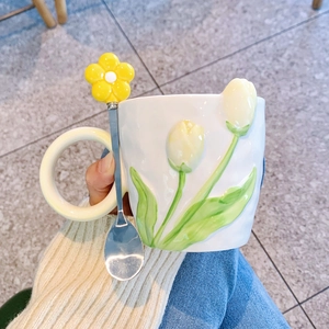 Close-up of ceramic tulip mug with 3D yellow flowers and matching floral metal spoon