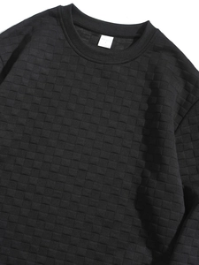 Detail of black long-sleeved crewneck sweatshirt with quilted checkerboard texture