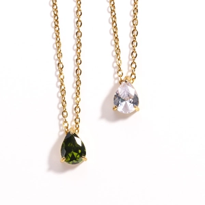 Detail of gold necklaces with pear-cut green and white cubic zirconia pendants