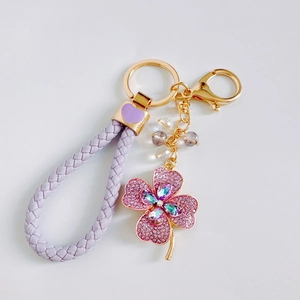Detail of purple braided leather strap and sparkling pink crystal clover keychain