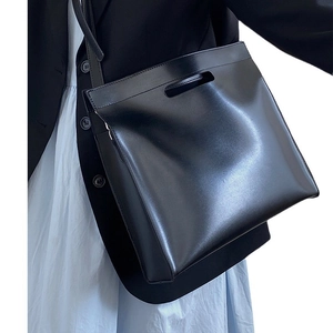 Minimalist black leather commuter tote bag shown with top handles and shoulder strap