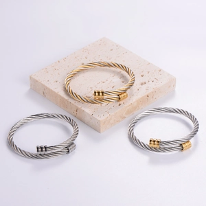 Detail of three-tone braided stainless steel cable bracelets on stone texture