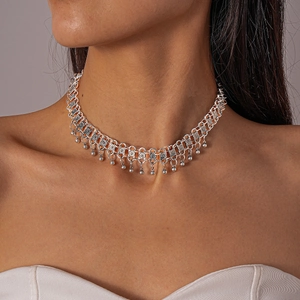 Detailed close-up of silver metal choker featuring intricate carved blocks and bead fringe
