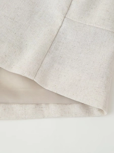 Detail view of beige linen fabric texture and stitching on the sleeveless top hem