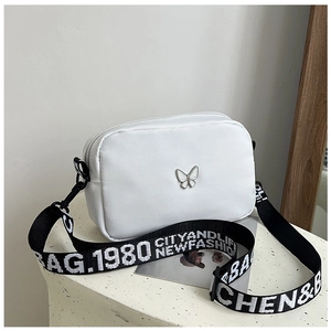 Detail of white nylon square bag featuring silver butterfly buckle and lettered strap