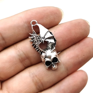 Gothic silver skull pendant with bat wings held in hand for jewelry making DIY
