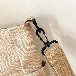 Close-up of durable beige canvas tote bag material and black plastic swivel hook