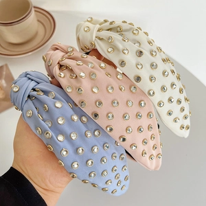 Close-up of knotted satin headbands in blue, pink and beige with sparkling rhinestones