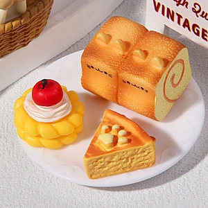 Close-up of miniature cat-themed resin bread and cake models on a white relief plate