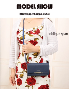 Model wearing dark blue leather crossbody bag with gold metal detail on floral dress