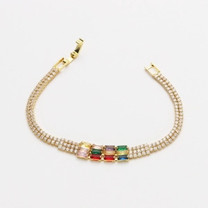 Dettaglio del bracciale dorato con doppia fila di zirconi bianchi e gemme rettangolari colorate