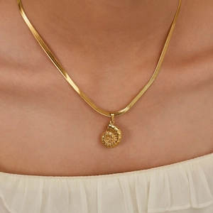 Detail of a golden conch shell pendant necklace with a sleek flat snake chain for women