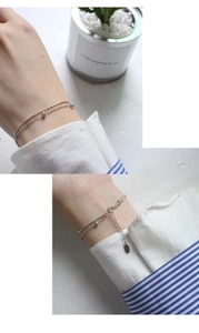 Detail of silver double-layered snake chain bracelet with beads on a woman's wrist