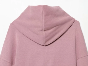Détail du sweat à capuche rose montrant la texture tricotée et la couture de l'épaule