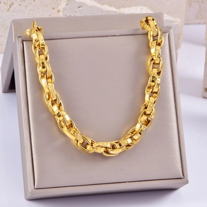 Detail of chunky gold chain link bracelet with engraved star patterns in jewelry box
