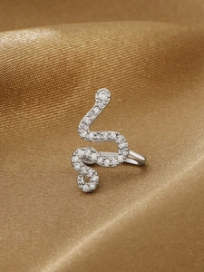Dettaglio del ear cuff a forma di serpente d'argento con cristalli pavé su seta dorata