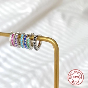 Macro detail of multicolored cubic zirconia stones on silver huggie earrings