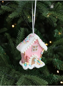 Pink gingerbread candy house Christmas ornament hanging on a pine tree branch