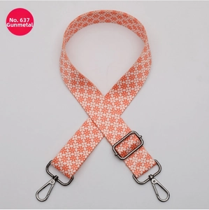 Detail view of adjustable ethnic bag strap with orange floral pattern and gunmetal hooks
