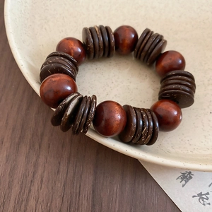 Close-up of coconut shell and wood bead bracelet on a ceramic plate with zen aesthetic