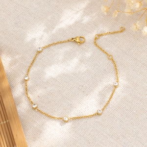 Bracelet élégant en acier titane doré avec des pierres en zircone sur un fond en tissu