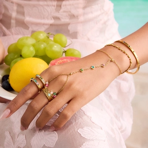Gold stainless steel bracelet and rings set with colorful stones on hand by a pool
