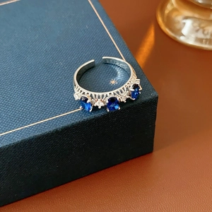 Détail d'une bague en dentelle argentée avec zircons bleu foncé sur écrin en cuir